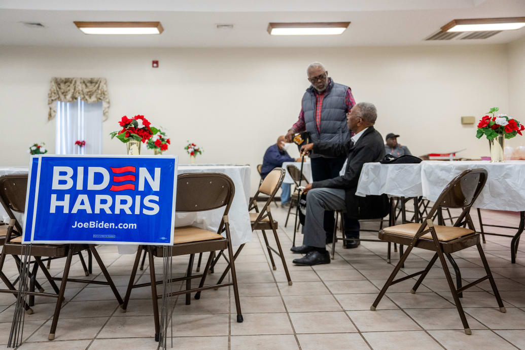  Two black men mill around a room filled with pro Biden posters.