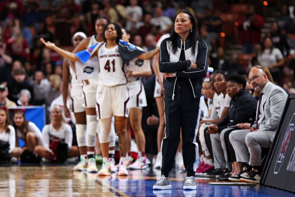 A photo of Dawn Staley in front of her team on a basketball court.