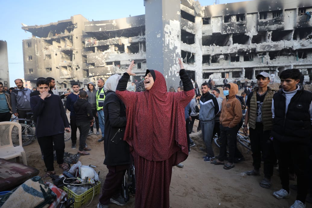 A photo of a woman mourning in front of a destroyed building in Gaza City.