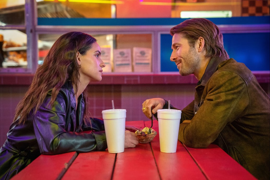 Adria Arjona and Glen Powell sit at a table in 'Hit Man'