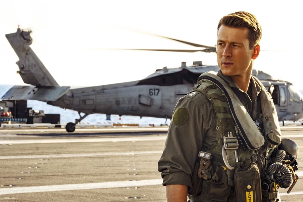 Glen Powell stands in front of a helicopter in 'Top Gun: Maverick'