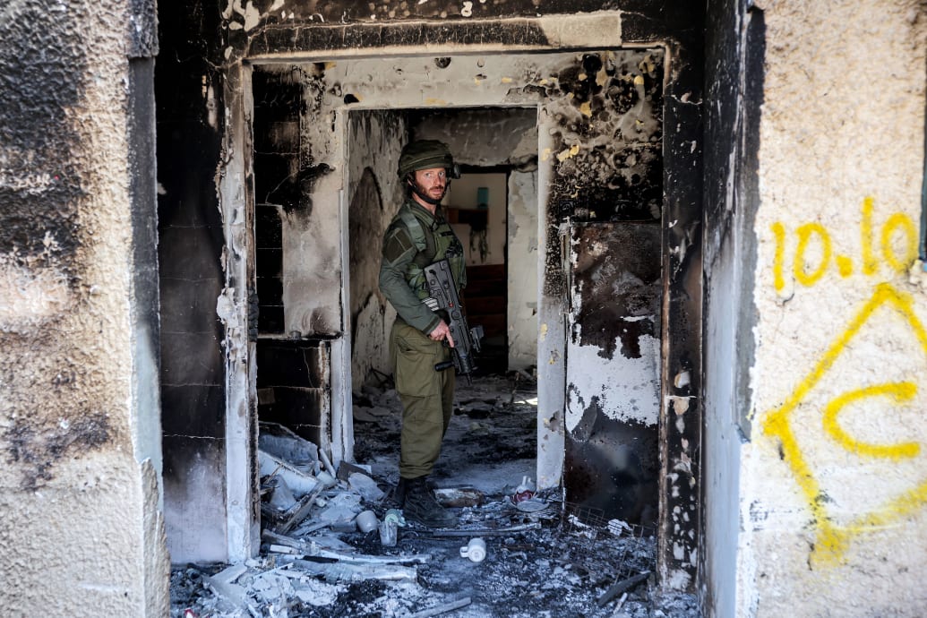An Israeli soldier stands inside of a burnt building in Kfar Aza in southern Israel near the Gaza Strip