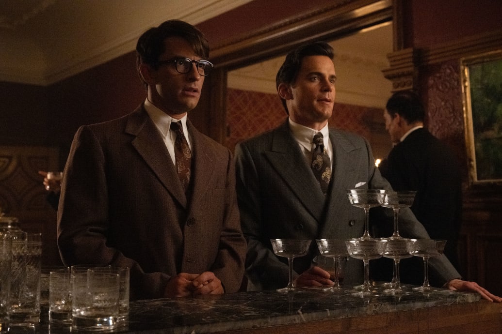 Jonathan Bailey and Matt Bomer stand next to each other at a bar in a still from ‘Fellow Travelers’