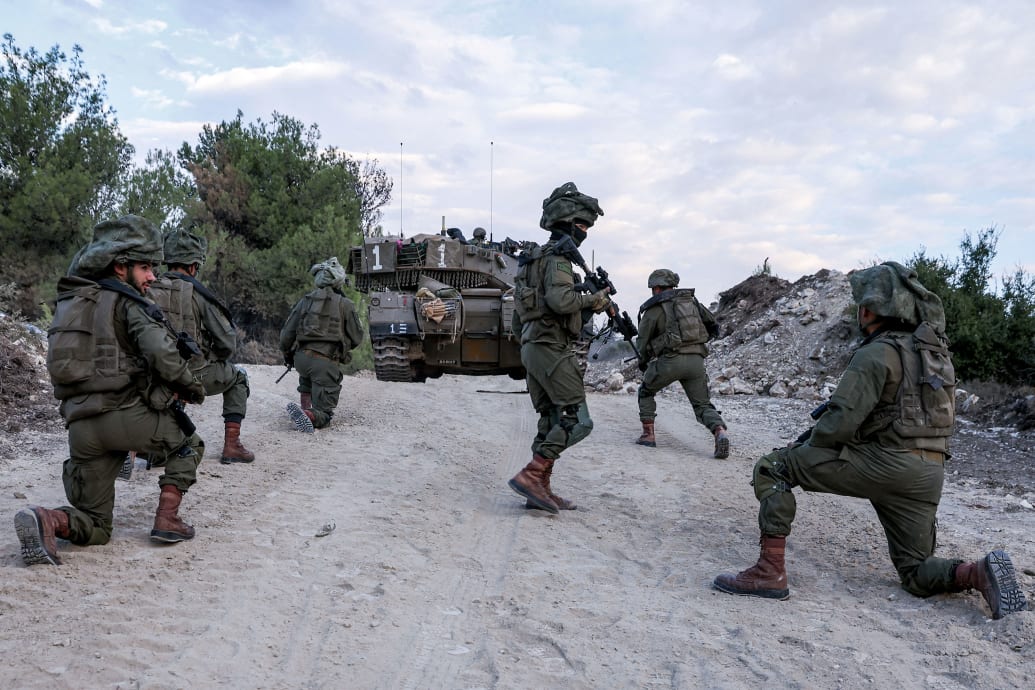 Israeli soldiers wait on a dirt road
