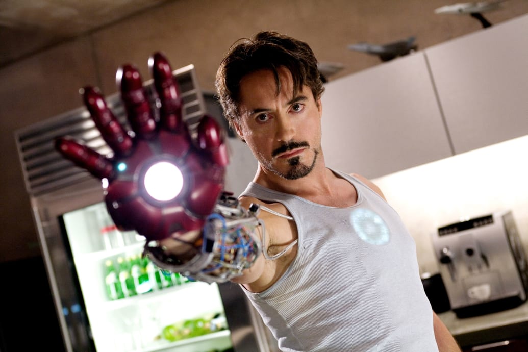 Robert Downey Jr. holding his hand up in the Iron Man suit in a still from ‘Iron Man’