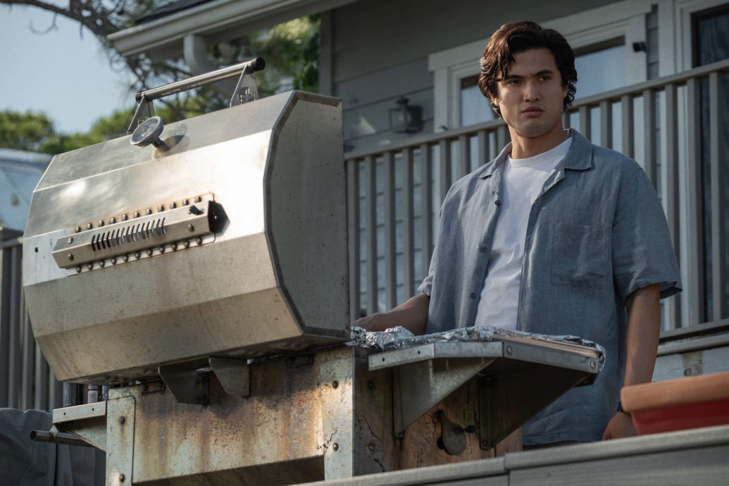 A picture of Charles Melton grilling in front of a BBQ in a still from ‘May December’