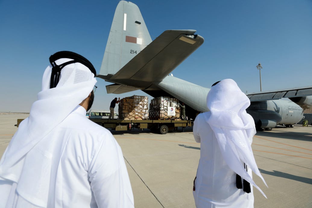 A photo shows the back of Qatari men who look on to a cargo plane in Qatar.