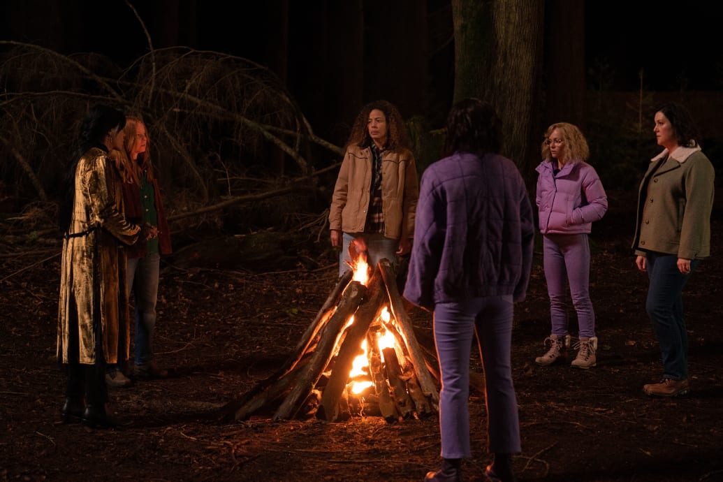 Simone Kessell as Lottie, Lauren Ambrose as Van, Tawny Cypress as Taissa, Christina Ricci as Misty and Melanie Lynskey as Shauna stand around a camp fire in a still from Yellowjackets