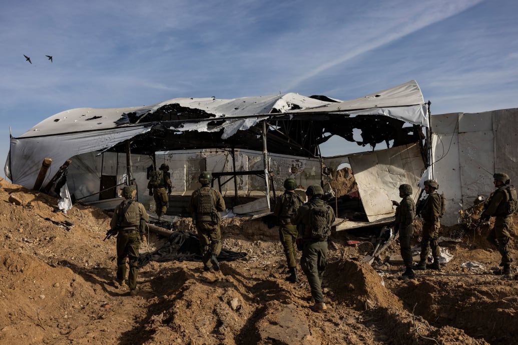 A photo shows the backs of IDF soldiers going into a torn tent camp in Gaza.