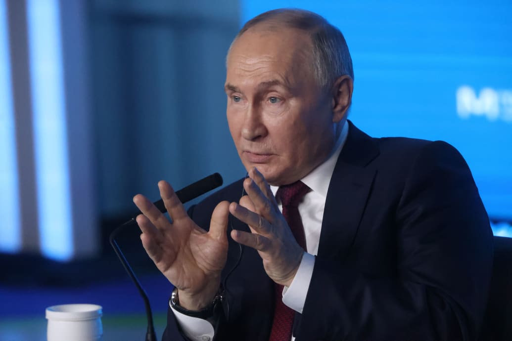 A picture of Vladamir Putin gesturing at a meeting.