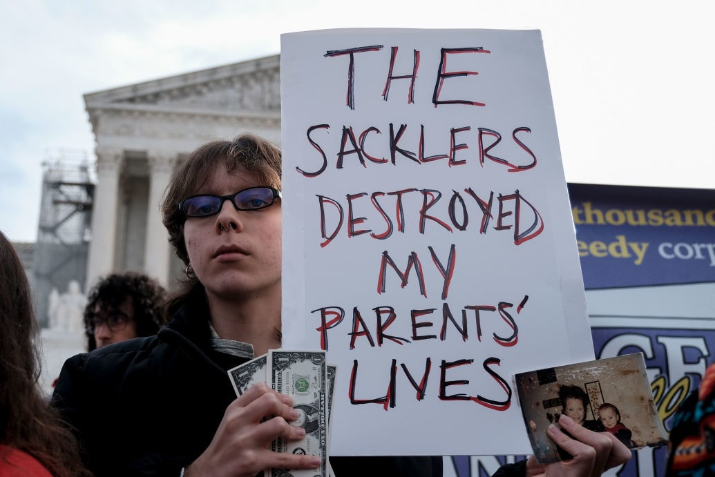 A young man holds a sign outside the Supreme Court. 