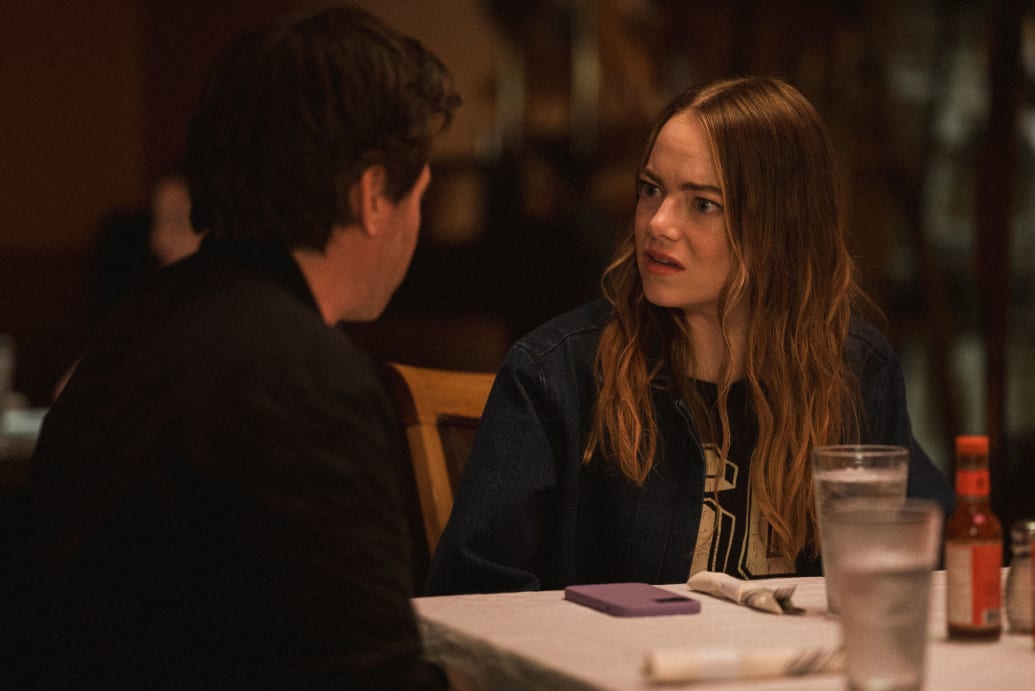 Emma Stone talks to Nathan Fielder while they sit at a dinner table in a still from ‘The Curse’