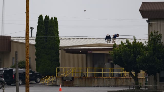 Two FBI investigators scan the roof of AGR International Inc, the building adjacent to the Butler Fairgrounds, from which alleged shooter Matthew Thomas Crooks fired at former President Donald J. Trump