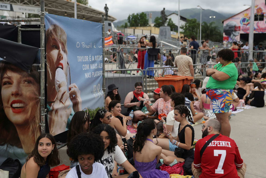 Taylor Swift fans sit outside of a stadium in Rio de Janeiro.