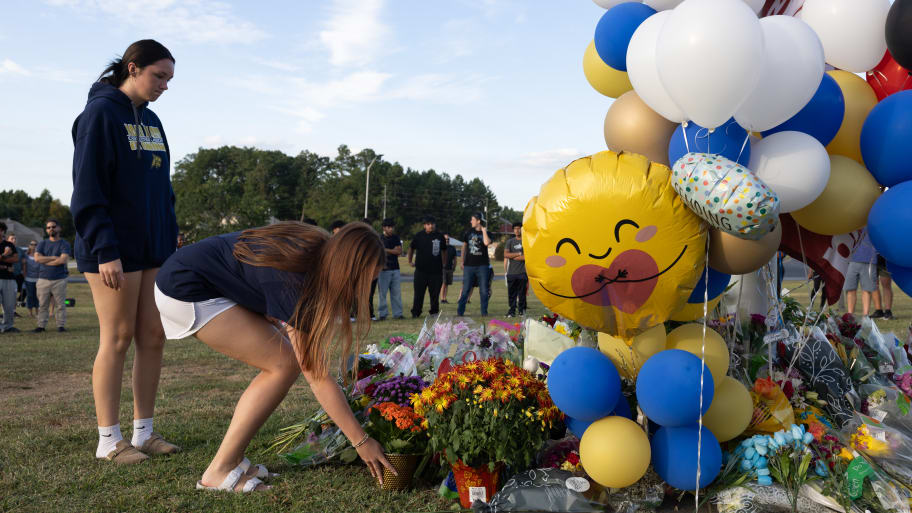 Two students place flowers at a memorial outside of Apalachee High School