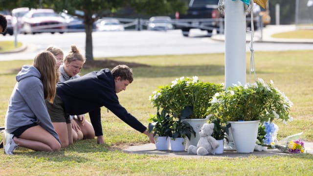 Students kneel in front of a makeshift memorial in front of Apalachee High School on September 5, 2024 in Winder, Georgia.