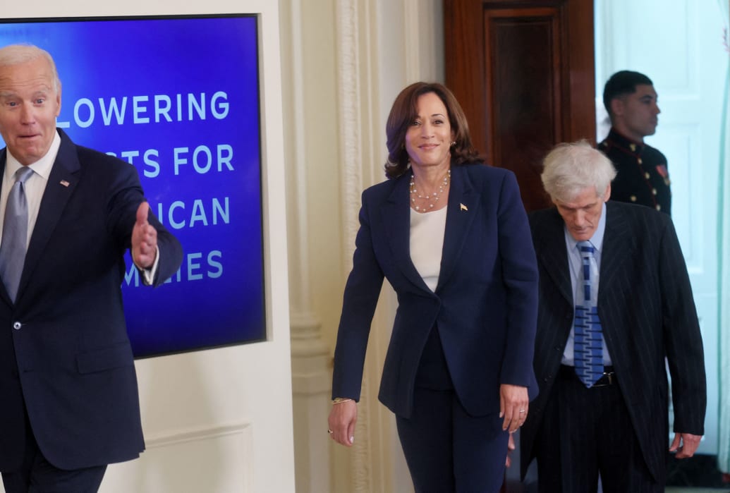 Kamala Harris walks behind Joe Biden in the White House