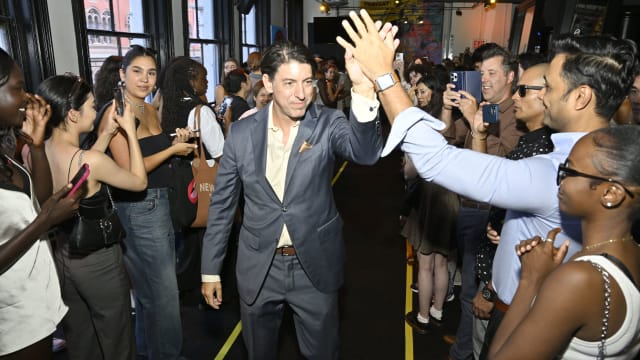 A photo of Patrick Walsh at an industry event, high-fiving his fans.