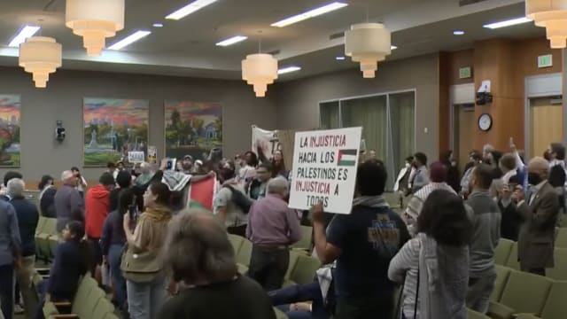 People chant and hold up signs during a debate on a resolution calling for a ceasefire in Gaza at the Sacramento City Council. 