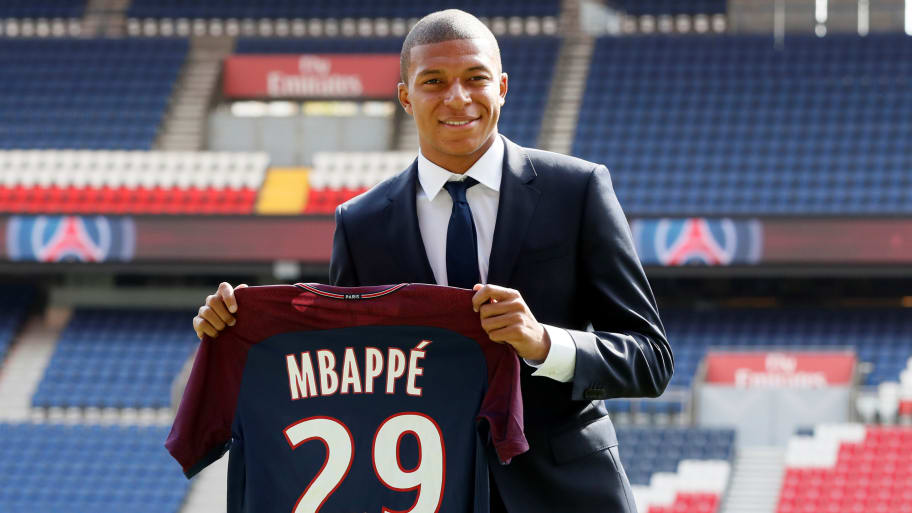 Paris St Germain signing Kylian Mbappe poses with the club shirt after a press conference.