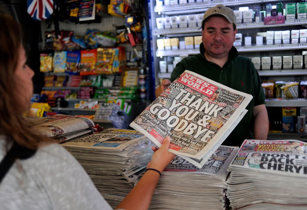 A woman buys a copy of the last edition of the British tabloid newspaper News of the World.