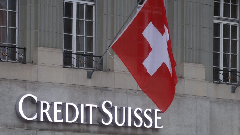 Switzerland's national flag flies above a logo of Swiss bank Credit Suisse in front of a branch office in Bern, Switzerland November 29, 2022. 