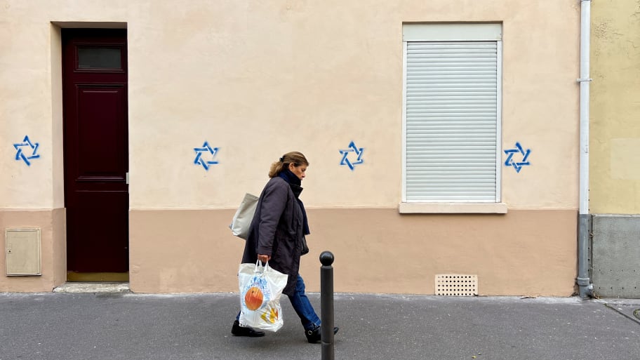 A woman walks past a building tagged with Stars of David in Paris, France, Oct. 31, 2023.