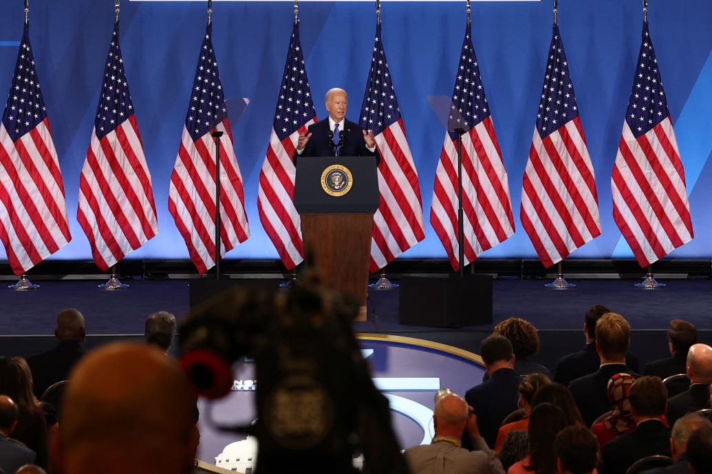 Joe Biden seen at a lectern surrounded by flags