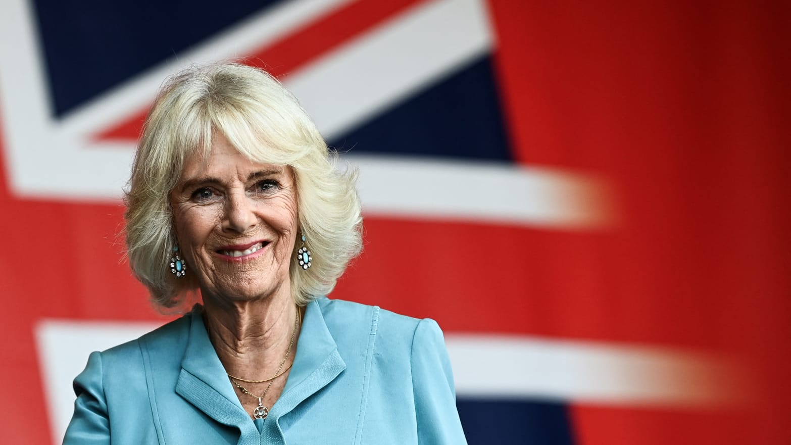 Britain's Queen Camilla smiles as she stands under a giant banner of the British Union flag during a visit to a festival in celebration of British and French culture and business at Place de la Bourse in Bordeaux, France, on September 22, 2023.