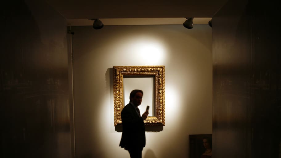 Man walks by a frame with no photo inside of it. 