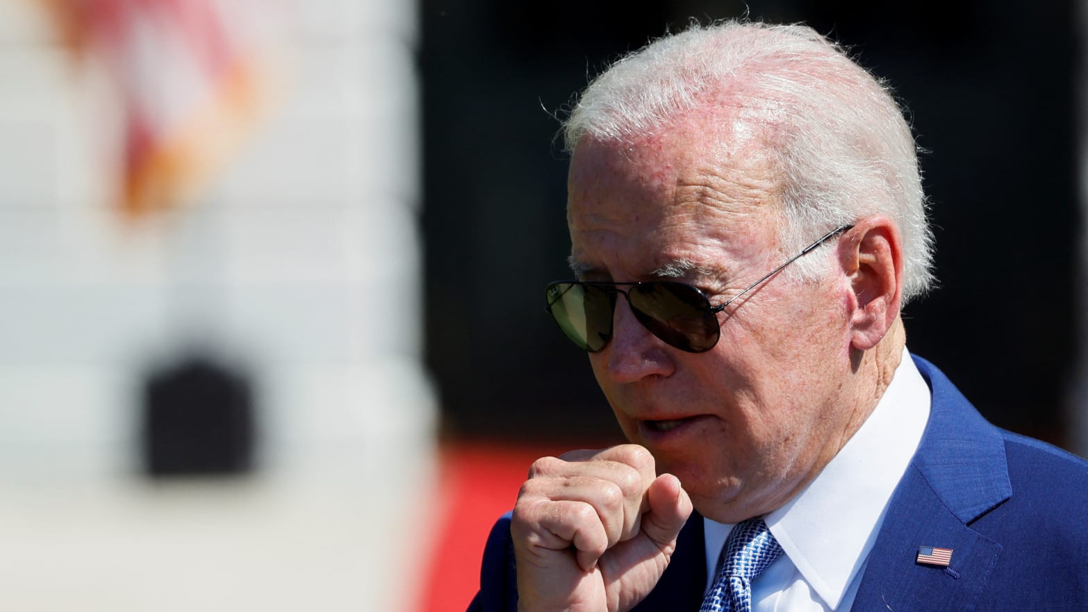Joe Biden coughs into his hand at an event.