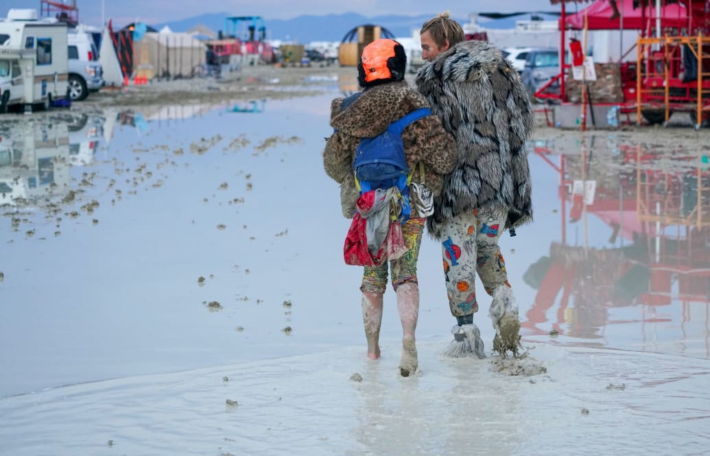 Photograph of a couple in the mud at Burning Man 2023