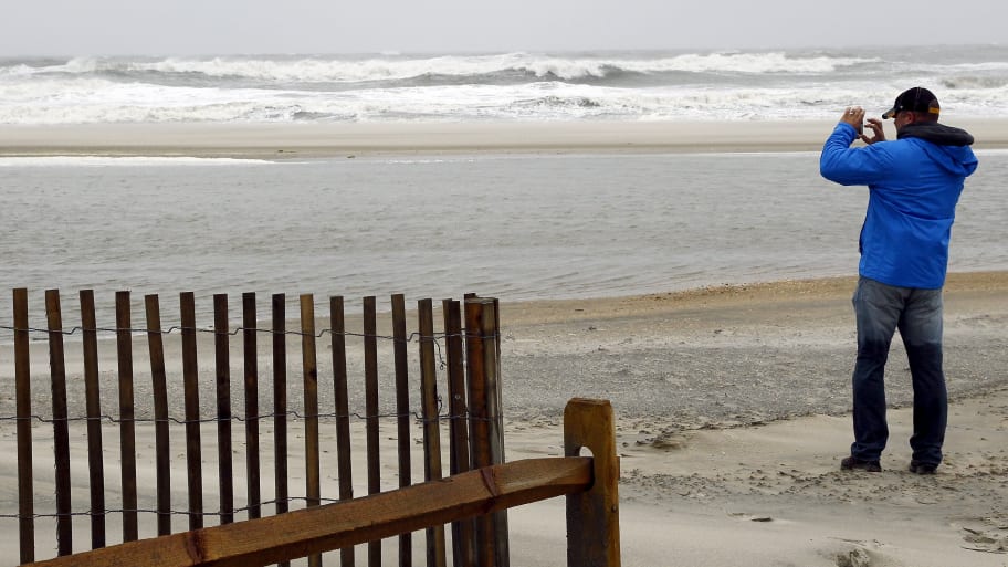 A visitor to the beach takes photographs of the storm surf with his cellphone camera as a nor-easter comes on shore in Ocean City, New Jersey, October 2, 2015.
