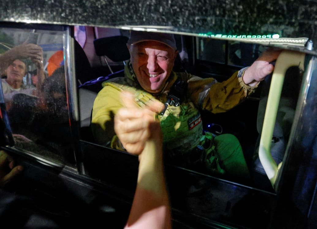 Yevgeny Prigozhin is shown in a car shaking hands with a supporter in Russia