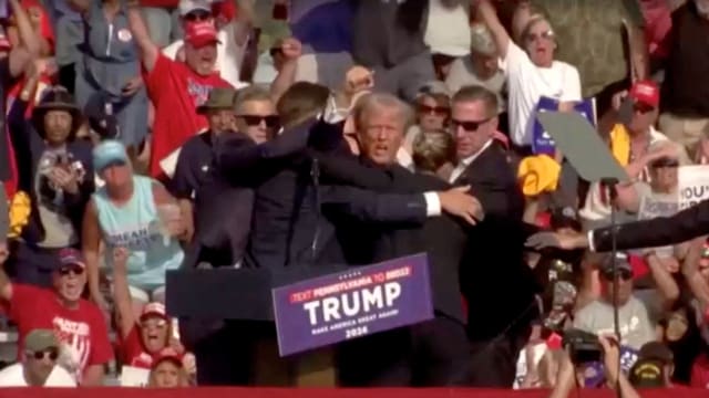 Republican presidential candidate and former U.S. President Donald Trump is assisted by security personnel after gunfire rang out during a campaign rally at the Butler Farm Show in Butler, Pennsylvania, July 13, 2024, in screen grab taken from video.