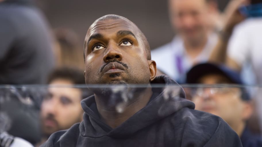Kanye West looks up as a glass barrier is in front of him.