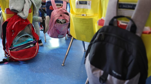 Student backpacks hang on the backs of classroom chairs in a New York City public school.
