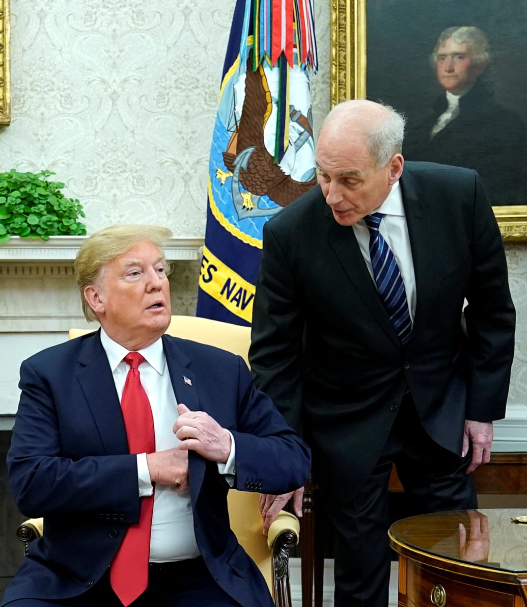 John Kelly whispers into Donald Trump’s ear.