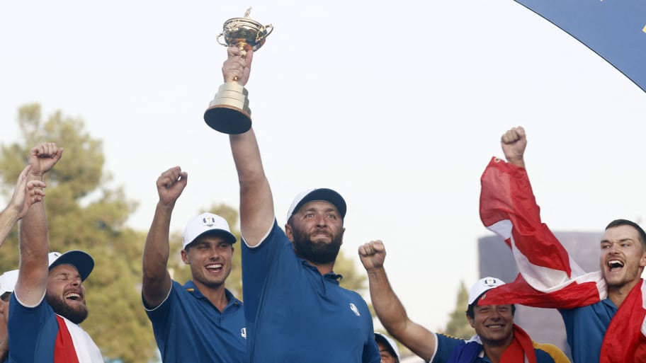 Jon Rahm holds the trophy aloft as he celebrates with teammates during the presentation after winning the Ryder Cup
