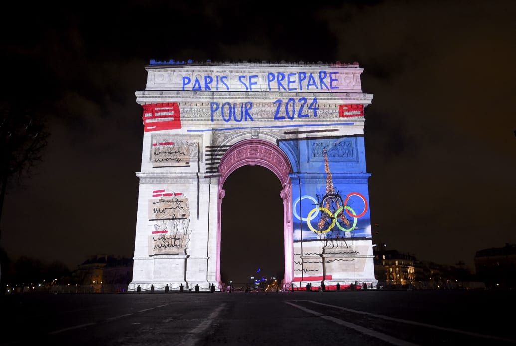 Photograph of the Arc de Triomphe in Paris with images depicting the 2024 Olympics projected on it.