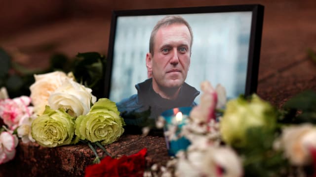 Flowers and a candle are placed next to a portrait of Russian opposition leader Alexei Navalny following Navalny’s death.