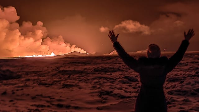 A local resident watch smoke billow as the lava colour the night sky orange from an volcanic eruption on the Reykjanes peninsula 3 km north of Grindavik, western Iceland on December 18, 2023. 