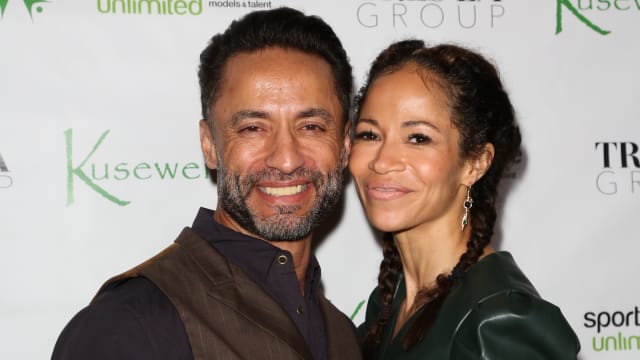 Actors Kamar de los Reyes and Sherri Saum pose for a photo on a step and repeat