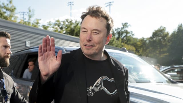 Elon Musk waves as he attends the men's final on day fourteen of the 2024 US Open Tennis Championships 