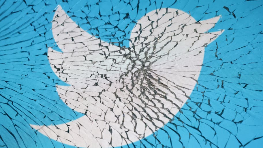 Twitter app logo is seen through broken glass in this illustration.