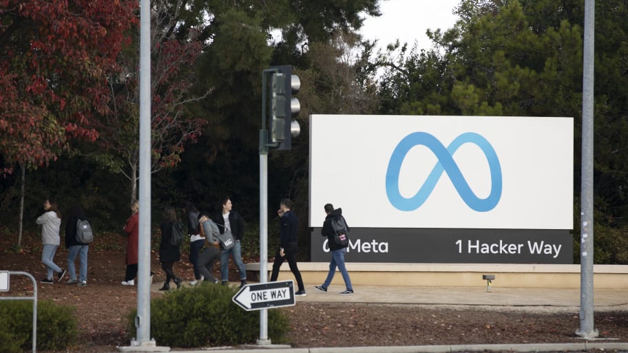 People leave after posing for photos in front of the logo of Facebook parent company Meta