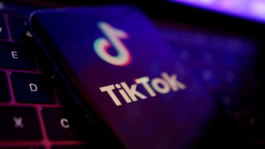 An illustration of the TikTok logo on a phone atop a laptop keyboard