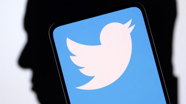 An illustration shows the Twitter logo on top of a silhouette of Elon Musk