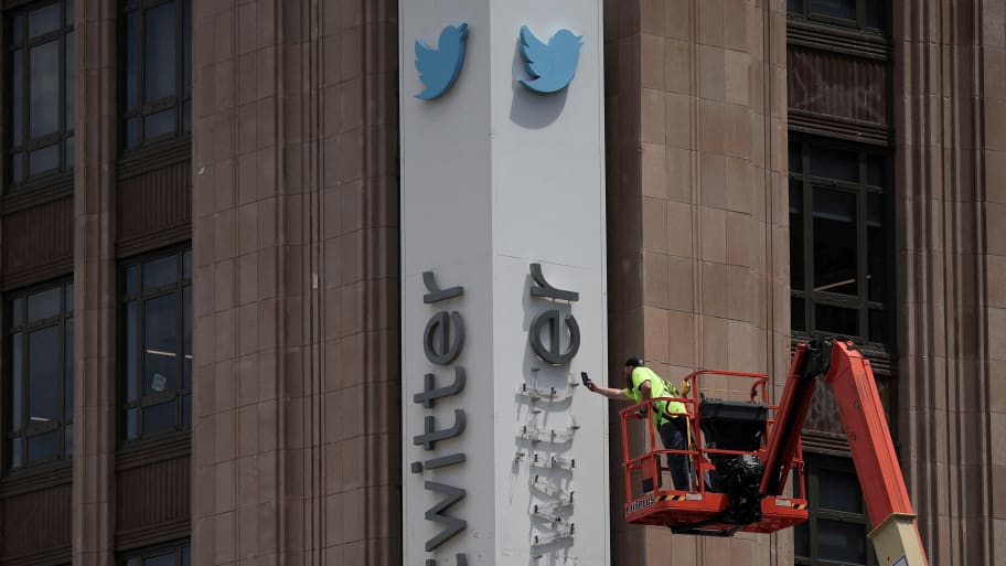 Worker takes down the old Twitter logo from HQ