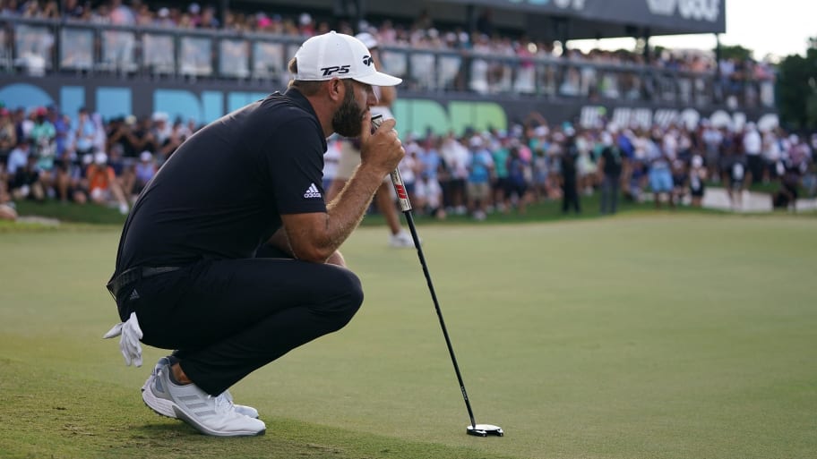 Golfer Dustin Johnson crouches as he holds a golf club on the green